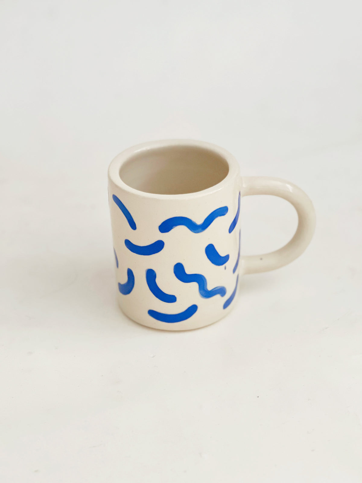 The fun squiggles design adds a touch of whimsy to your cup of coffee or tea. Made by hand, this ceramic mug is durable and perfect for everyday use. Enjoy your favorite beverage in style with our unique Squiggles Mug.