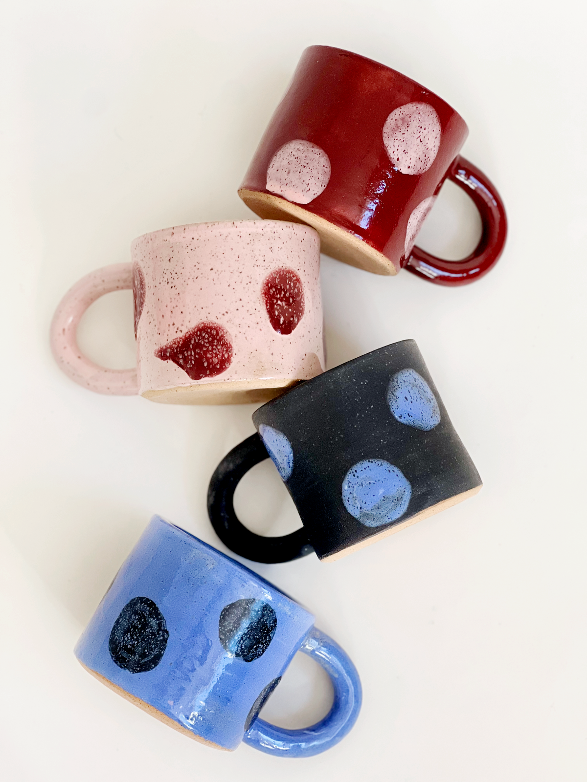 Four ceramic mugs with polka dot patterns on a white background