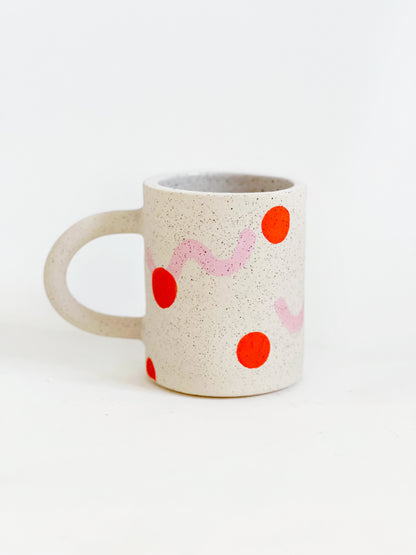 This handmade ceramic mug features playful polka dots over different shapes, adding a colorful and fun touch to your daily coffee or tea routine. Handcrafted with attention to detail, this unique mug is a must-have for any ceramic collection. Enjoy your favorite drink in a playful yet elegant way.
