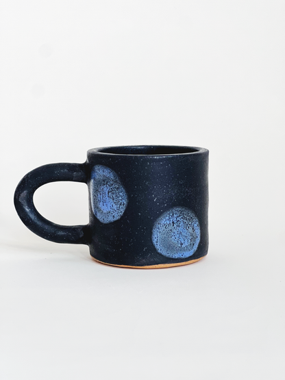 Pink speckled mug with red dots designs on a white background