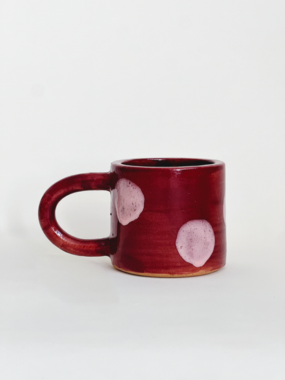 Red ceramic mug with pink polka dots on a white background