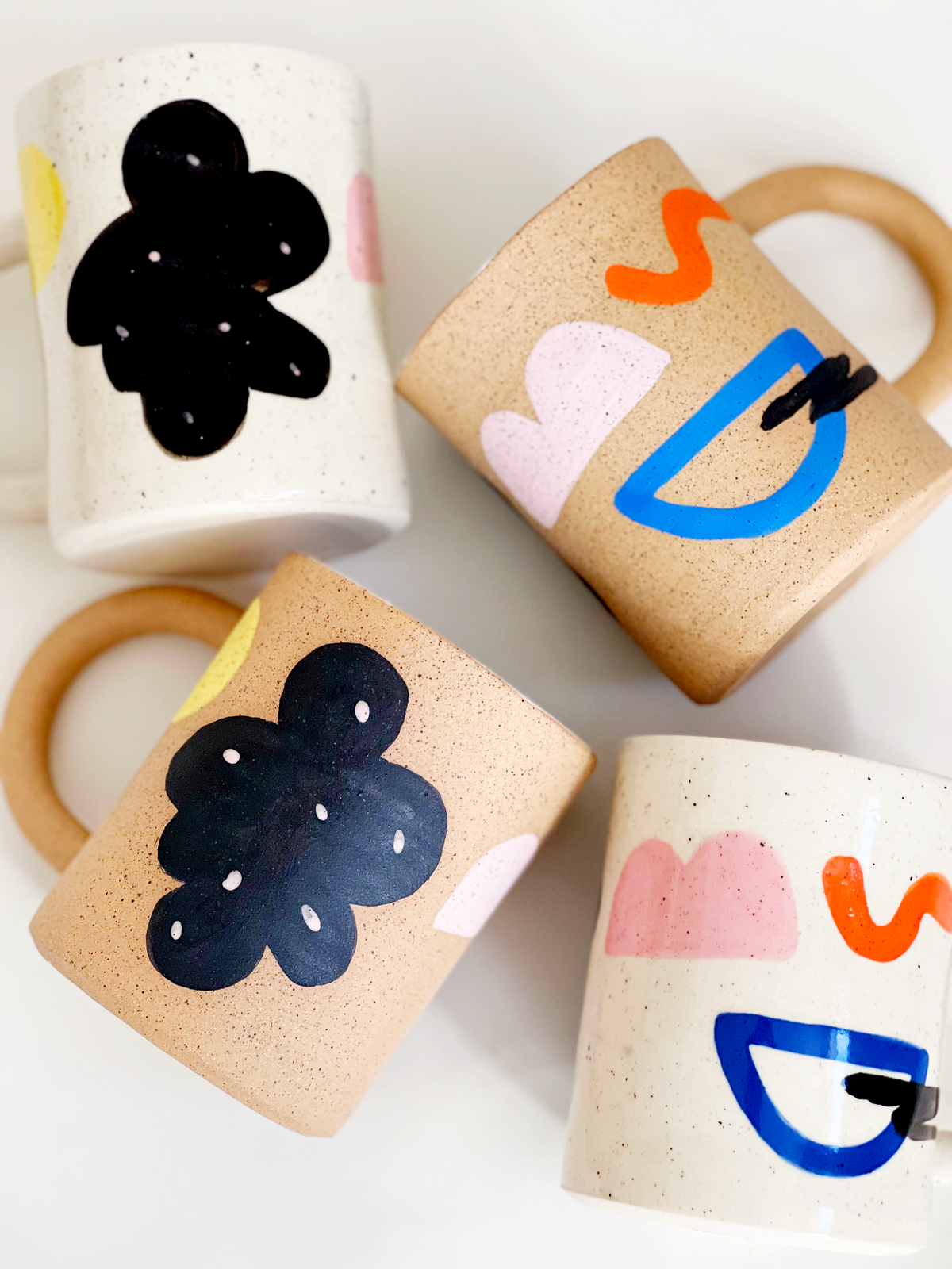 Four ceramic cups with abstract face designs on a white background